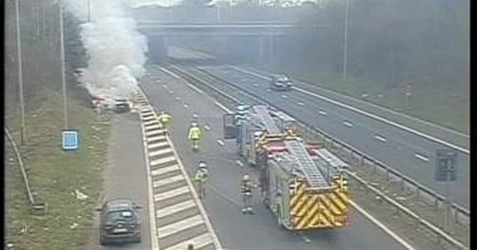 The car goes up in flames and closes part of the busy motorway while emergency services rush to the scene

