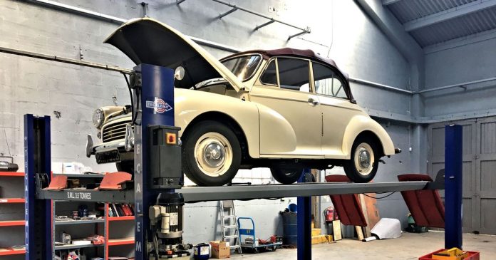 A classic Morris car having work done on a maintenance bay at the Great British Car Journey