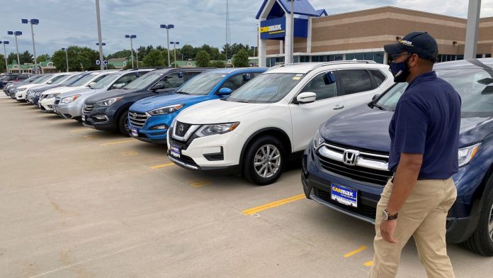 Brandon Parrum, general manager of CarMax&#39;s Des Moines store, walks past some of the many vehicles that customers can arrange to buy online and collect at the store using "contactless" curbside pickup, a service the U.S. used car retailer launched during the coronavirus disease (COVID-19) pandemic, in De Moines, Iowa, U.S. July 29, 2020.
